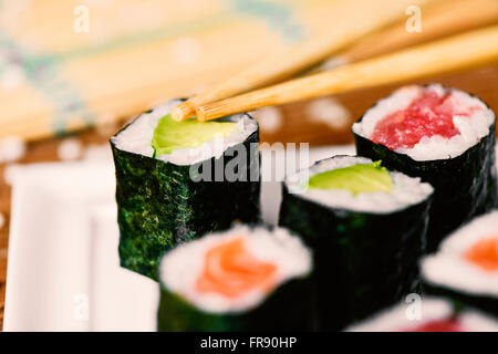 Primo piano di un bianco di ceramica vassoio con alcune diverse makizushi, riempito con avocado, tonno e salmone Foto Stock