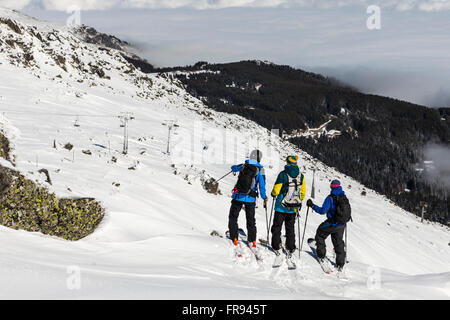 Tre i free riders sono prepairing per sciare giù un snowy Rocky Mountain top. Foto Stock