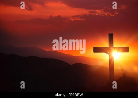 La luce di Cristo antico crocifisso ligneo sul deserto durante il tramonto panoramico. Una croce cristiana tramonto sullo sfondo. Foto Stock