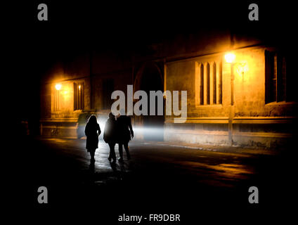 Tre stagliano gli studenti a piedi passato biblioteca Bodleian Library nella notte tempo verso Radcliffe Camera in Oxford, Regno Unito Foto Stock