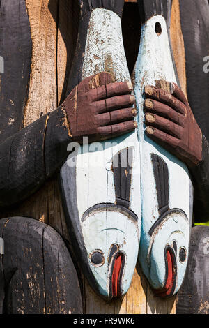 Dettaglio di una figura tenendo premuto il salmone intagliato in un totem, Totem Bight State Historical Park, Ketchikan, a sud-est di Alaska, STATI UNITI D'AMERICA, molla Foto Stock