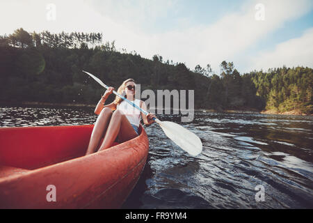 Giovane donna kayak sul lago. Felice giovane donna canoa in un lago. Foto Stock