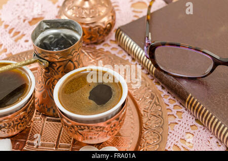 Il caffè turco è servita in un tradizionale bagno turco tazza di caffè in  un vassoio di rame Un bicchiere di acqua con un petalo di rosa e le delizie  turche sul