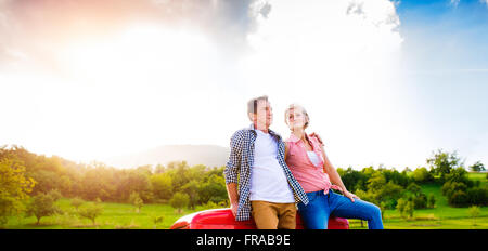 Coppia senior seduti nel retro del rosso carrello elevatore di prelievo Foto Stock