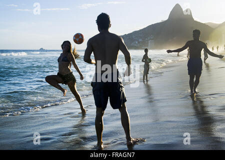 I bagnanti che giocano a calcio sulla spiaggia di Ipanema con i DOI Fratelli incidentali Foto Stock