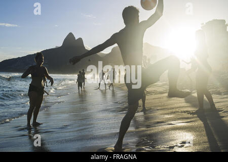 I bagnanti che giocano a calcio sulla spiaggia di Ipanema con i DOI Fratelli incidentali Foto Stock