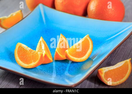 Freschi fette di arancia servito sulla piastra blu Foto Stock