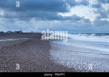 Persone lontane e barche sulla spiaggia tempestosa in inverno, Cley North Norfolk REGNO UNITO Foto Stock