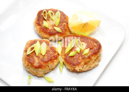 Torte di pesce serviti con limone e lo scalogno Foto Stock