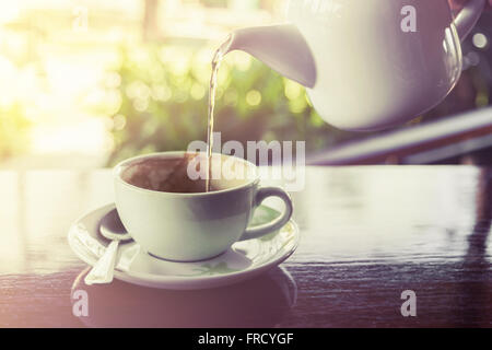 Tazza di caffè con spruzzi d'acqua da hot pot su legno e blur sullo sfondo, in stile vintage, il fuoco selettivo Foto Stock