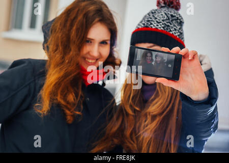 Due belle ragazze facendo selfie su sfondo bianco Foto Stock