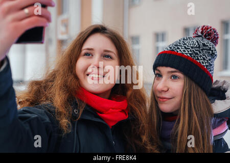 Due belle ragazze facendo selfie su sfondo bianco Foto Stock