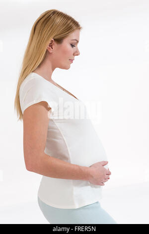 Casualmente vestito attraente donna incinta in piedi a casa Foto Stock