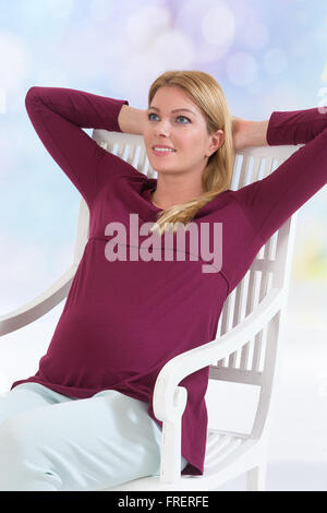 Casualmente vestito attraente donna incinta in piedi a casa Foto Stock