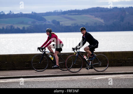 Due persone in bicicletta lungo la passeggiata lungo il fiume su un caldo sole di mattina di primavera a Dundee, Regno Unito Foto Stock