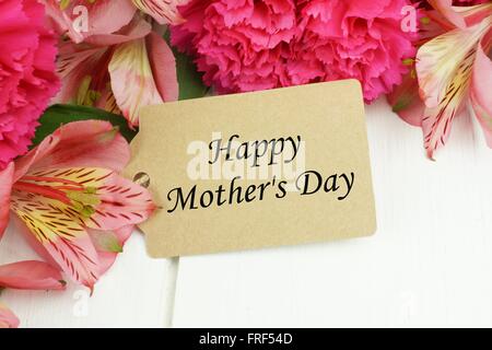Felice la Festa della mamma regalo tag close up con rosa e garofano giglio fiori bianchi contro uno sfondo di legno Foto Stock