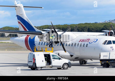 Meccanico è fare manutenzione per aereo jet -ATR 42-, di -Swiftair-, parcheggiato al di fuori della pista, in aeroporto di Madrid. Foto Stock