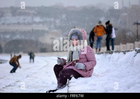 Giovane ragazza in un cappotto rosa ben avvolte da Baku Bulvar nella neve, nel capitale dell'Azerbaigian. Foto Stock