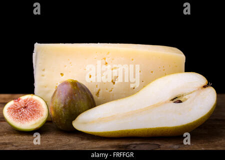Pera, formaggio e figura su legno gustoso antipasto sfondo nero Foto Stock