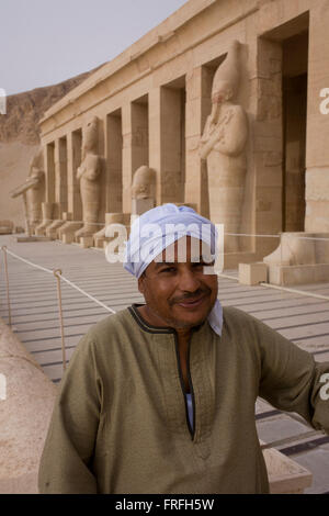 Ritratto di una guida locale vicino i colossi dei faraoni presso gli antichi egiziani Tempio di Hatshepsut vicino alla Valle dei Re, Luxor, la Valle del Nilo in Egitto. Il tempio mortuario della Regina Hatshepsut, Djeser-Djeseru, si trova sotto le scogliere a Deir el-Bahari ("il monastero del Nord'). Il tempio mortuario è dedicata al dio sole Amon-Ra ed è considerato uno dei monumenti di incomparabile di antico Egitto.' Il tempio era il luogo del massacro di 62 persone, la maggior parte dei turisti, da islamici il 17 novembre 1997. Foto Stock