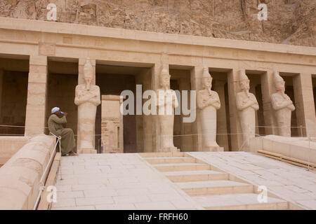 Una guida locale sorsi acqua vicino i colossi dei faraoni presso gli antichi egiziani Tempio di Hatshepsut vicino alla Valle dei Re, Luxor, la Valle del Nilo in Egitto. Il tempio mortuario della Regina Hatshepsut, Djeser-Djeseru, si trova sotto le scogliere a Deir el-Bahari ("il monastero del Nord'). Il tempio mortuario è dedicata al dio sole Amon-Ra ed è considerato uno dei monumenti di incomparabile di antico Egitto.' Il tempio era il luogo del massacro di 62 persone, la maggior parte dei turisti, da islamici il 17 novembre 1997. Foto Stock