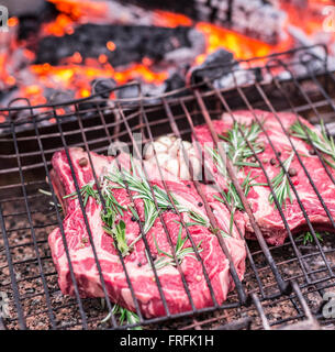 Occhio di nervatura bistecche e grill con un fuoco che brucia dietro di loro. Foto Stock