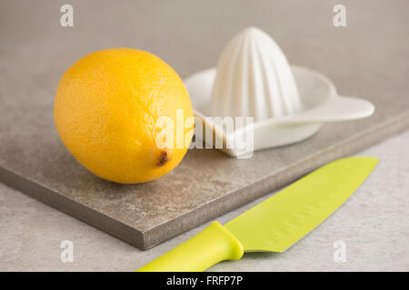 Limone, coltello spremitore e sul tavolo di cucina. Concetto di preparazione del cibo e la cucina con frutta fresca. Foto Stock