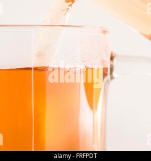 Il tè versando nella coppa di vetro. Dettaglio di una bevanda calda. Concetto di bevanda calda colazione o un tè. Foto Stock