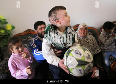 Nablus, West Bank, Territorio palestinese. 22 Mar, 2016. Ragazzo palestinese Ahmed Dawabsha, 5, che hanno subito gravi ustioni in un incendio doloso da sospetti Jewish gli utenti malintenzionati sulla sua casa di famiglia lo scorso luglio e in cui il suo fratello più giovane, Ali, e i suoi genitori morirono entrambi, è accolto da parenti dopo il ritorno dalla Spagna dove ha incontrato il Real Madrid stelle, a suo nonno in casa la Cisgiordania villaggio di Duma vicino a Nablus Marzo 22, 2016. Ahmed Dawabsha suo zio e i suoi nonni tornò in Spagna dove hanno incontrato i giocatori della squadra di calcio spagnola (credito Immagine: © Nedal Eshtayah/immagini APA vi Foto Stock