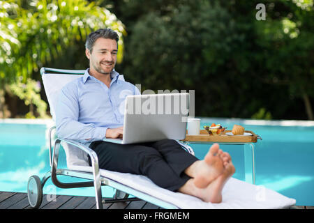 Smart uomo utilizzando laptop vicino alla piscina Foto Stock