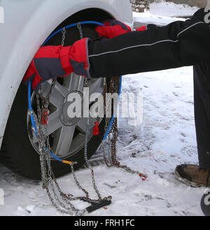 Installare le catene da neve in auto pneumatico invernale sulla neve Foto Stock