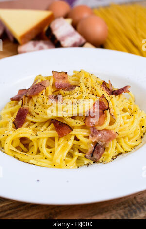 Tradizionale pasta italiana spaghetti alla carbonara con pancetta e formaggio e agg tuorlo sulla piastra bianca Foto Stock