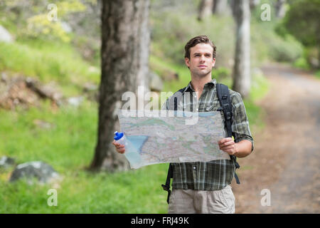Escursionista in piedi con la mappa sul sentiero nella foresta Foto Stock