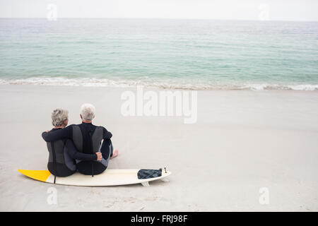 Vista posteriore del giovane seduto sulla tavola da surf Foto Stock