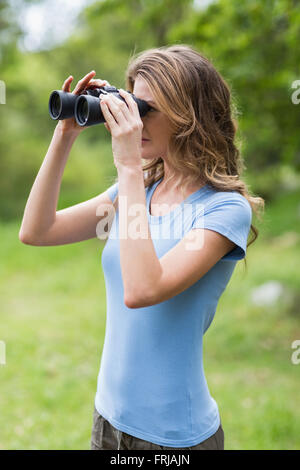 Giovane donna guardando attraverso il binocolo Foto Stock