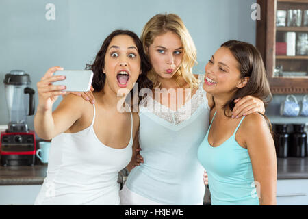 Amici facendo facce tenendo selfie sul telefono Foto Stock