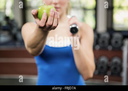 Donna che mantiene una mela verde in palestra Foto Stock