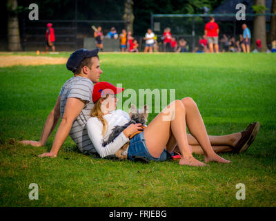 Giovane con cane guarda la partita di baseball, al Central Park di New York City, Stati Uniti d'America. Foto Stock