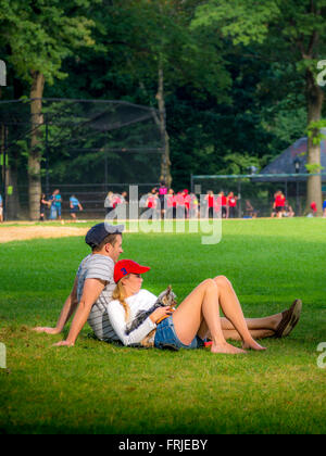 Giovane con cane guarda la partita di baseball, al Central Park di New York City, Stati Uniti d'America. Foto Stock