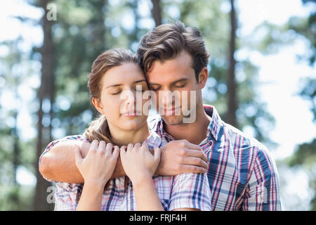 Coppia con gli occhi chiusi in piedi nella foresta Foto Stock