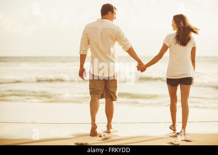 Felice coppia romantica sulla spiaggia al tramonto. Giovani innamorati in vacanza. Foto Stock