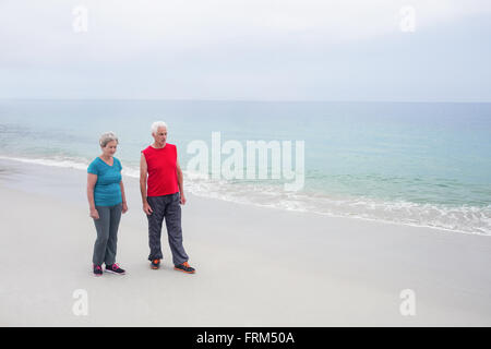 Coppia senior permanente sulla spiaggia Foto Stock