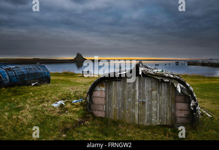 Lindisfarne Castle e le aringhe capannoni in barca che circondano il porto ancora oggi in uso dai pescatori per il lavoro e lo storage Foto Stock