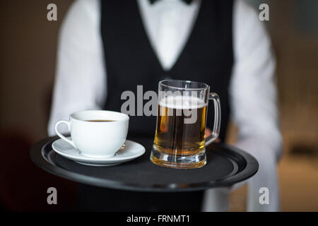 Cameriere tenendo il vassoio con la birra Foto Stock