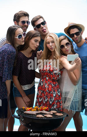 Gruppo di amici prendendo un selfie vicino alla piscina Foto Stock