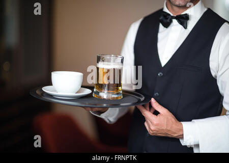 Cameriere tenendo il vassoio con la birra Foto Stock