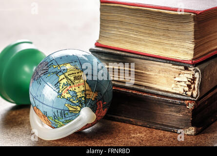 Pila di libri vecchi e globo in primo piano Foto Stock