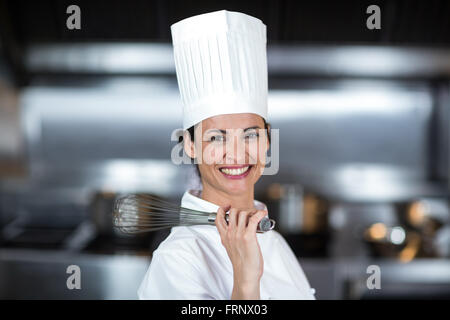 Ritratto di donna sorridente chef holding frusta Foto Stock