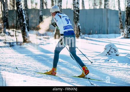 Atleta maschio sciatore durante la gara di foresta in stile classico. Il vapore durante la respirazione durante il campionato di Chelyabinsk in cross-country Foto Stock