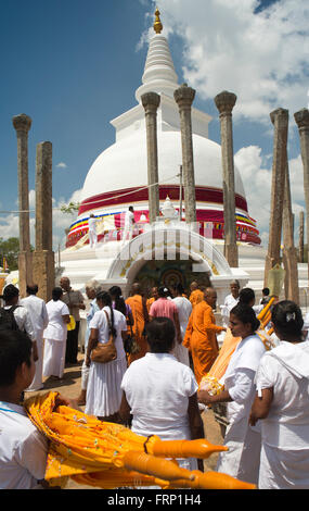 Sri Lanka, Anuradhapura Dagoba Thuparamaya, fedeli alla base della pagoda dopo la puja Foto Stock